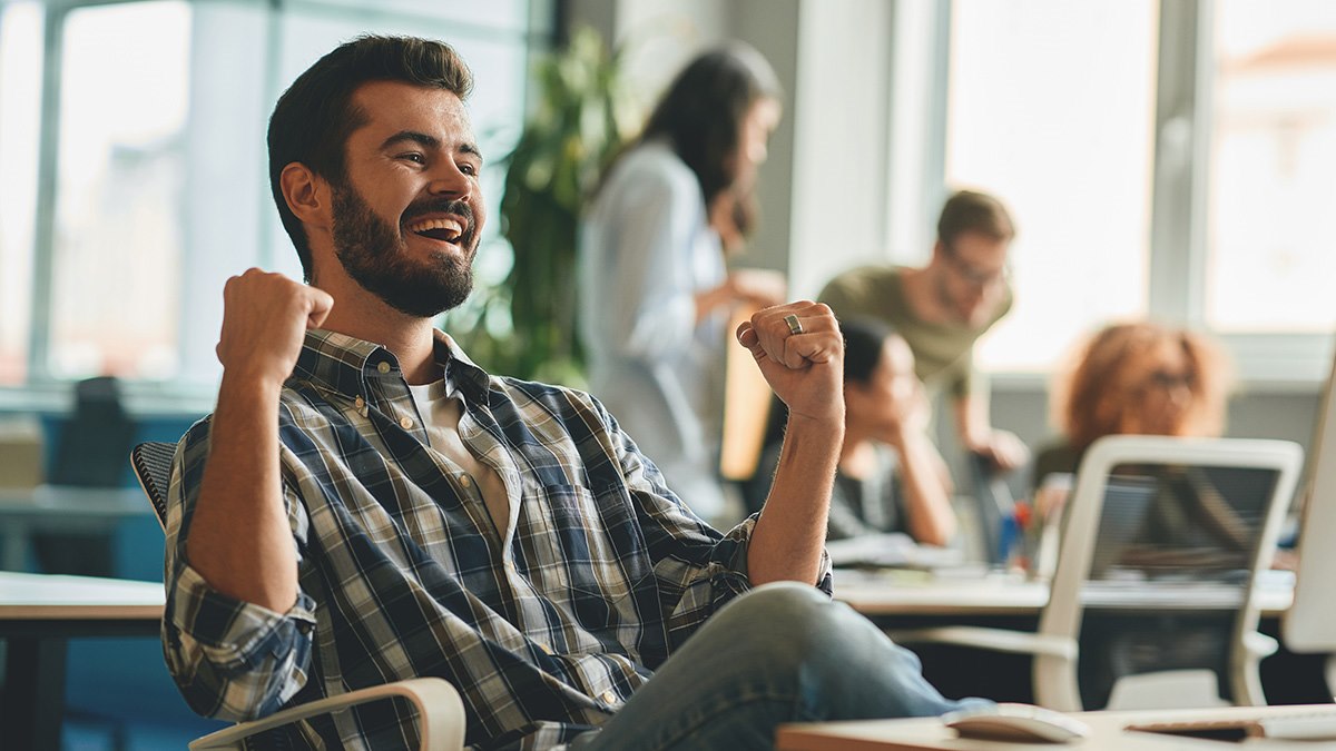 Мужчина-миллениал радуется успеху на работе в офисе