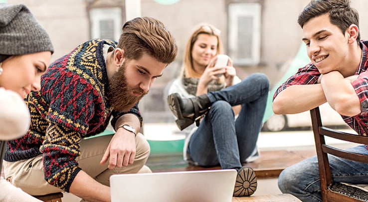 Команда креативных миллениалов на перерыве работает за ноутбуком в неформальной обстановке