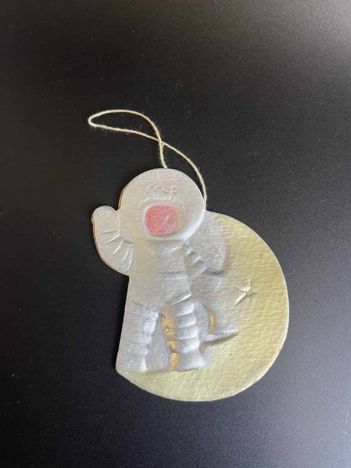 Картонная елочная игрушка-космонавт на фоне Луны