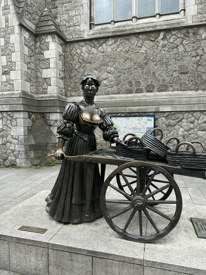 Статуя женщины с тележкой, на глаза наклеены гугли-айз