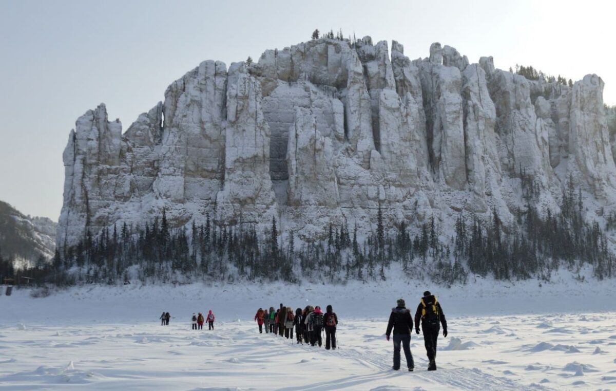 Группа туристов на фоне заснеженных скал Ленских столбов