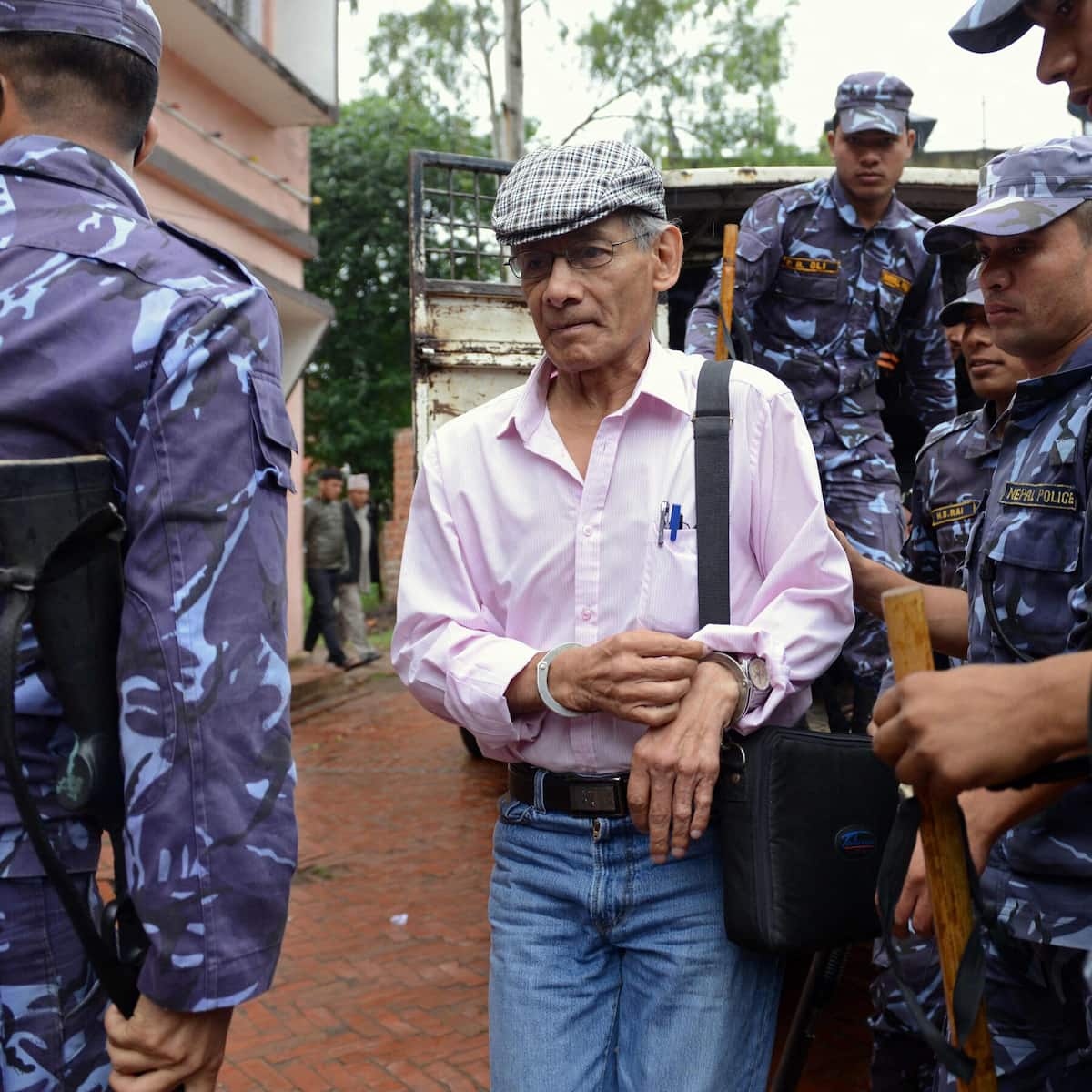 Шарль Собрадж в наручниках под конвоем непальской полиции в 2022 году