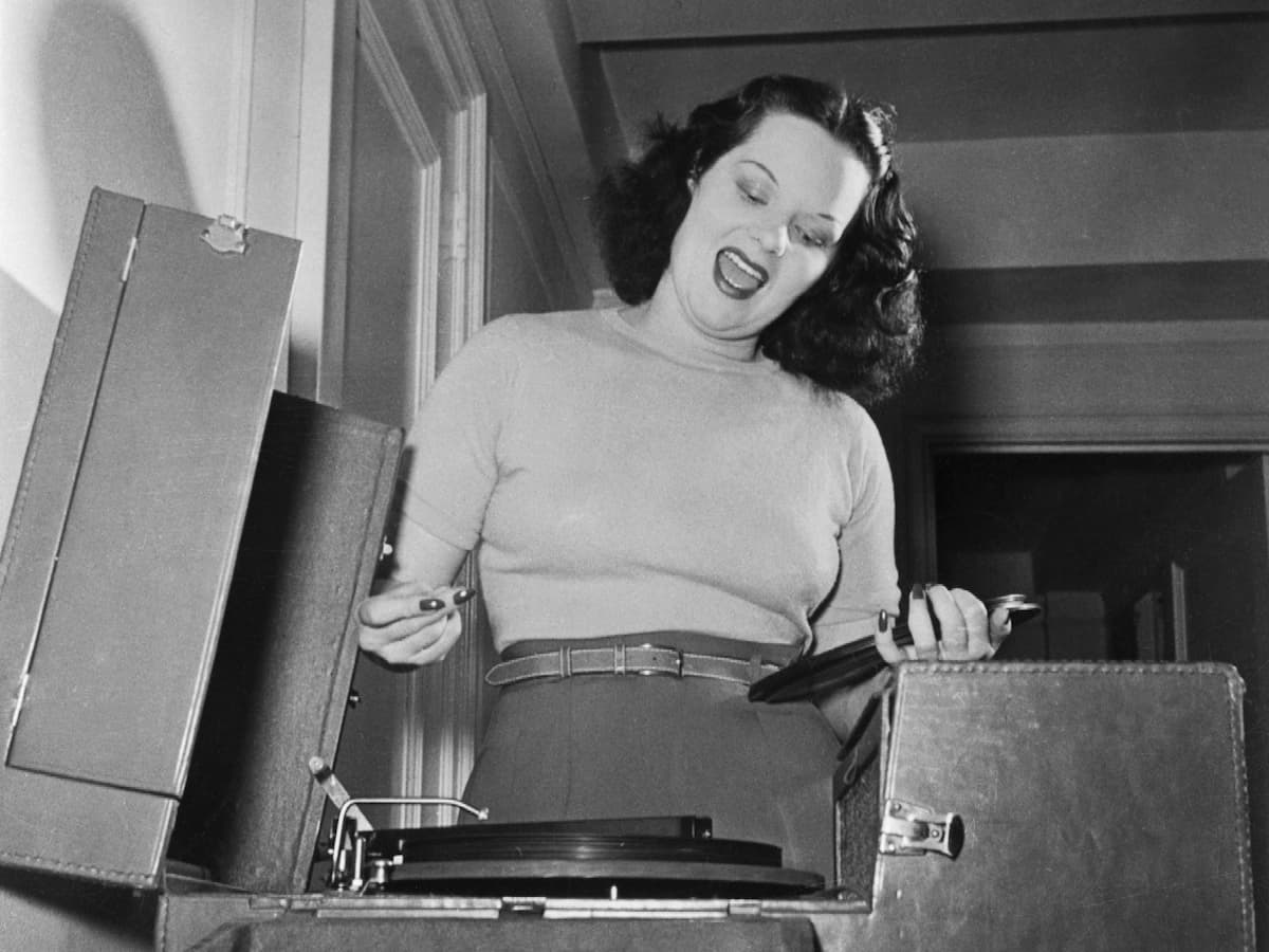 Вирджиния Хилл играет на граммофоне и поет эмоционально