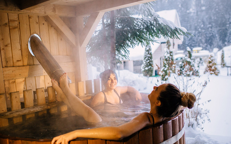 Девушки сидят в горячей бочке у русской бани зимой
