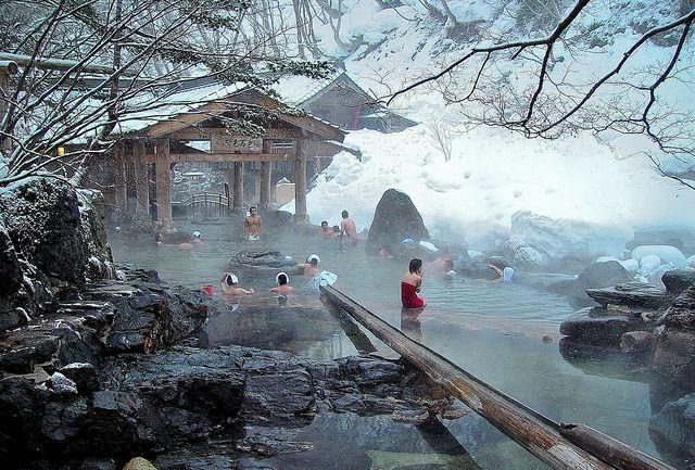 Люди расслабляются в горячем источнике на фоне заснеженного пейзажа