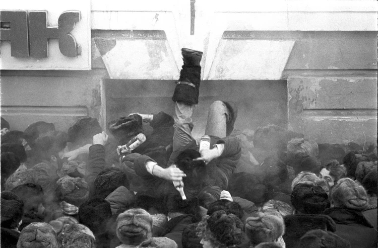 Толпа людей в давке у магазина в очереди за водкой в 1990-е годы