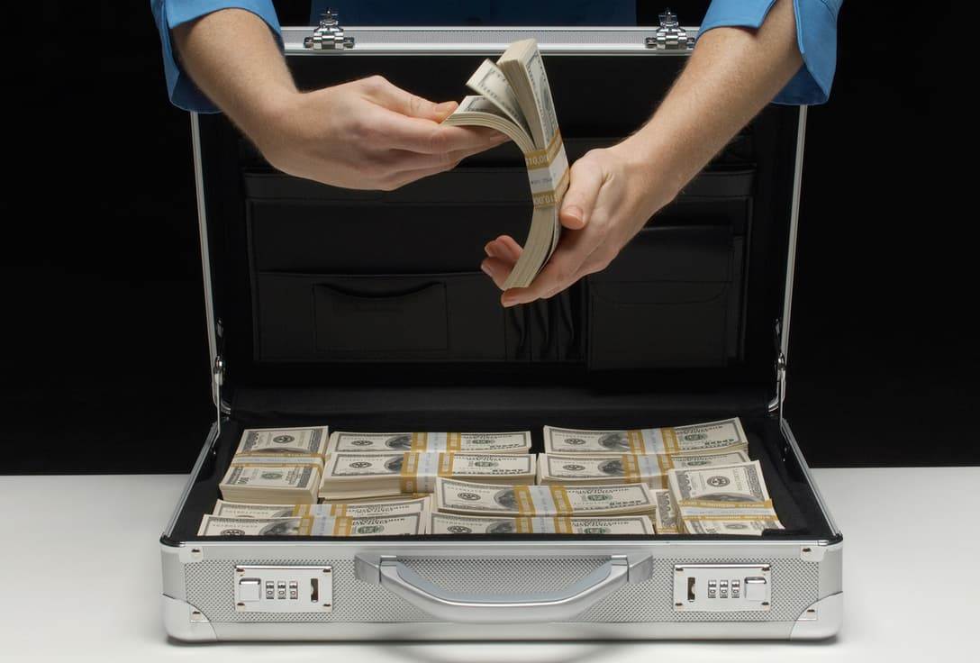 Мужчина держит пачки долларов внезапное богатство меняет жизнь