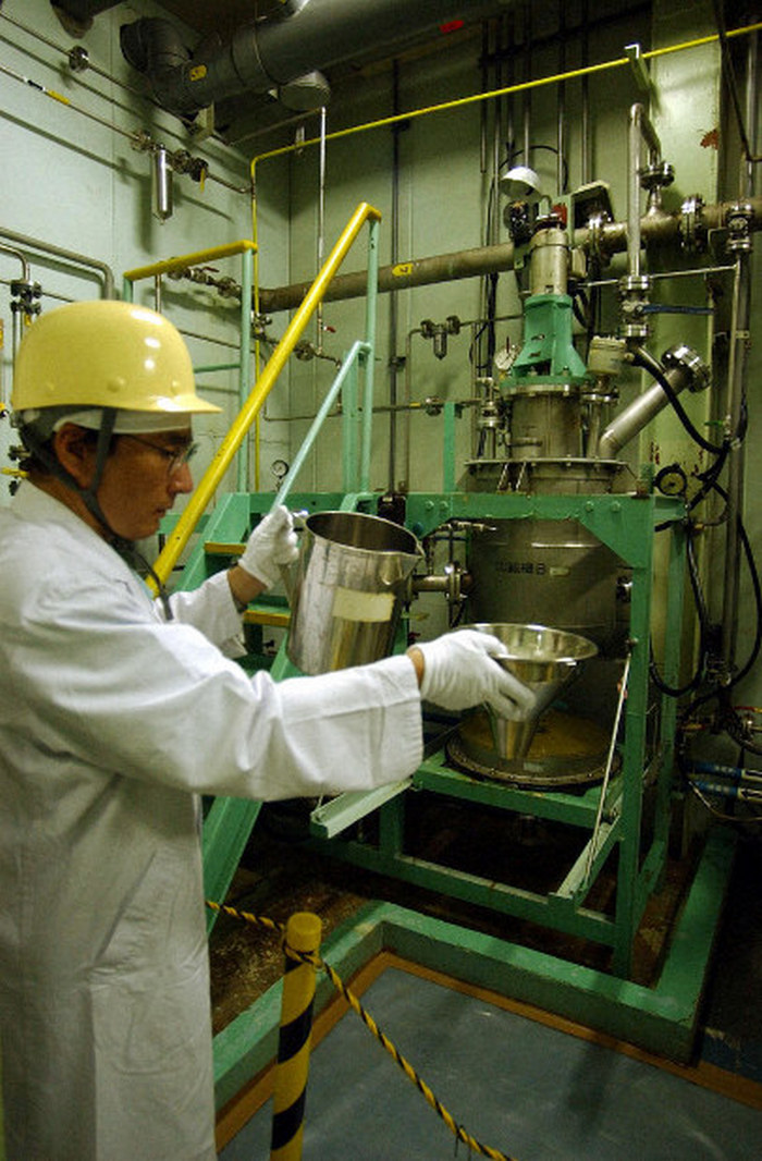 Техник JCO отмеряет ядерное топливо специальной лабораторной посудой — дозы урана измеряются в десятках граммов