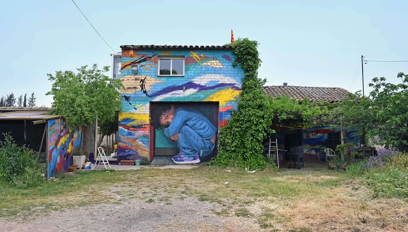 Мурал грустящего мальчика работы Ориола Аруми на воротах