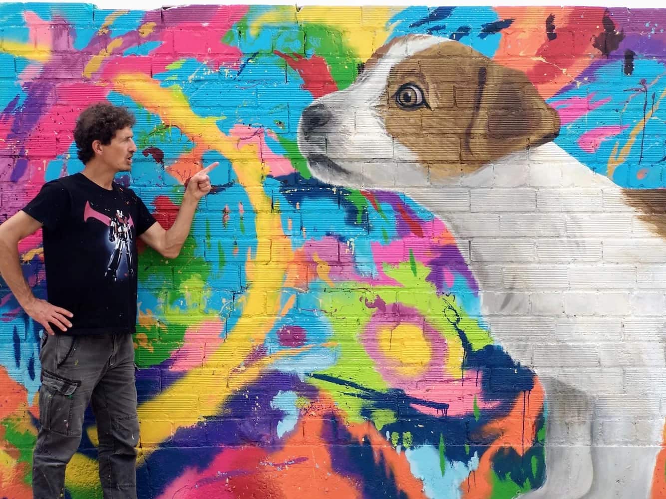Ориол Аруми рядом с муралом с собакой на разноцветной стене