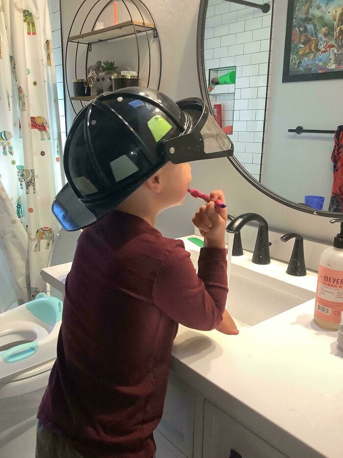 Мальчик в пожарном шлеме чистит зубы