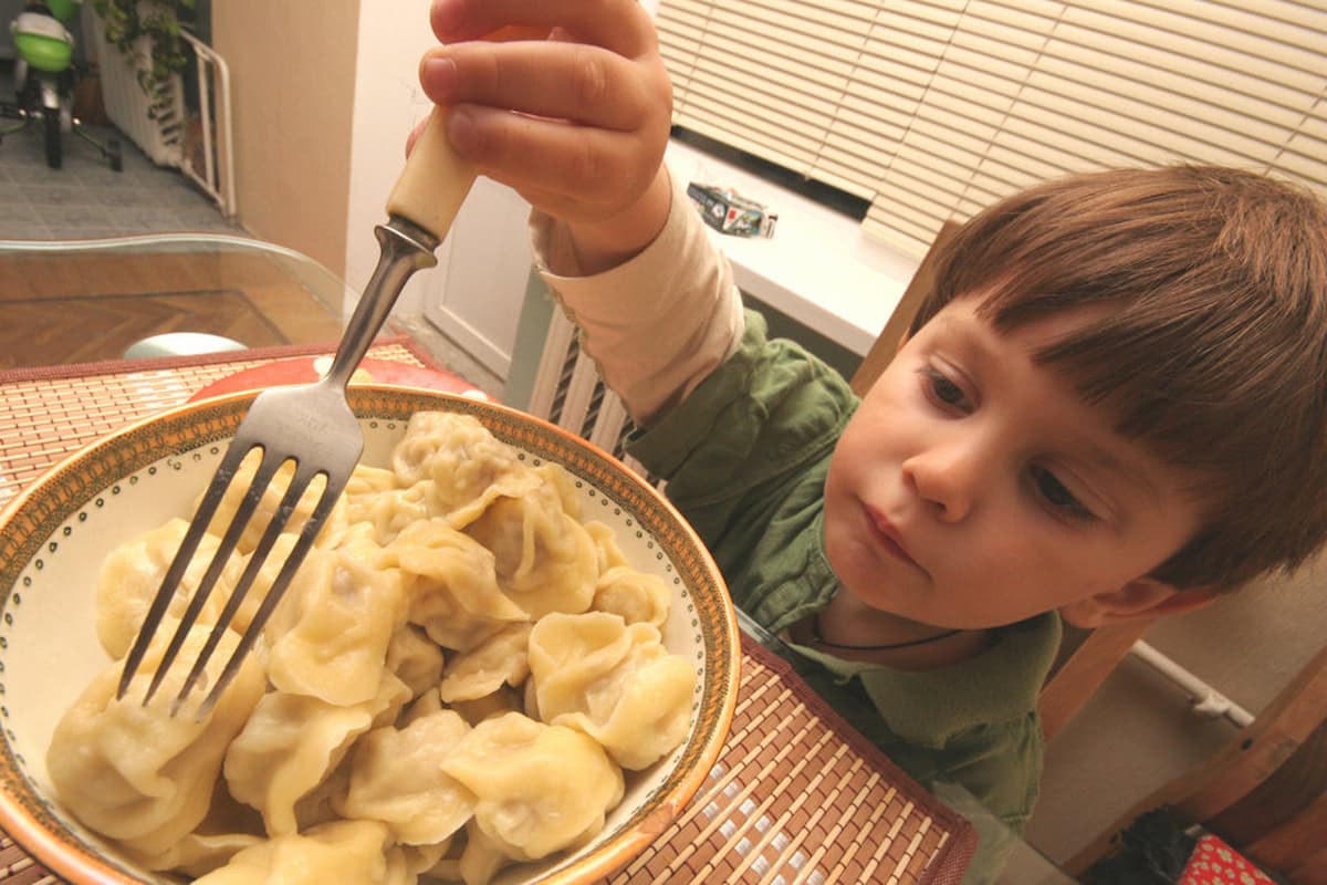 Мальчик ест пельмени
