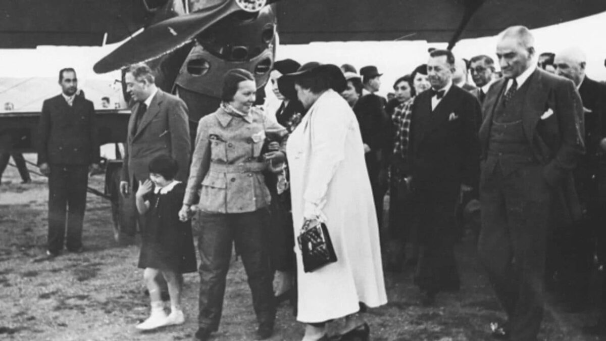 Сабиха Гёкчен и Мустафа Кемаль Ататюрк с группой людей стоят рядом с самолетом