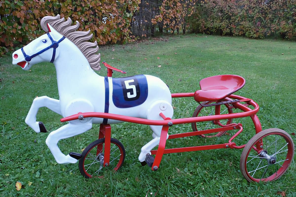 Конь педальный СССР. Металлическая игрушка в виде лошади с жокейской повозкой на трёх колёсах. Ярко-красный корпус, белая грива. СССР, 1960-е годы.