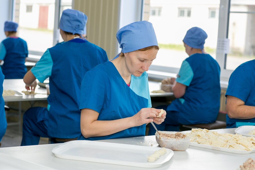 Работница пельменного производства лепит пельмени вручную