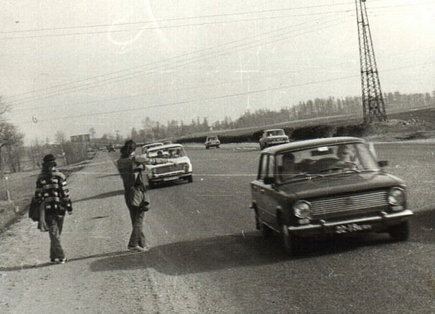 Молодые хиппи с рюкзаками голосуют на трассе, путешествуя автостопом по СССР