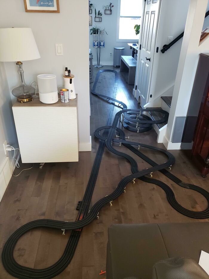 Чёрная трасса для машинок петляет по деревянному полу гостиной