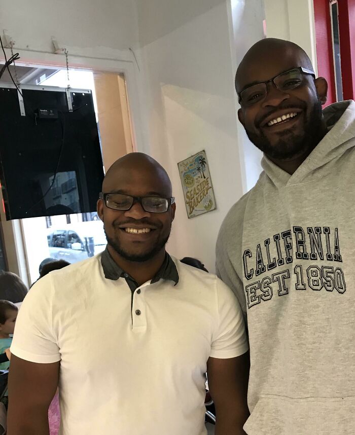 Два улыбающихся темнокожих мужчины в очках стоят рядом