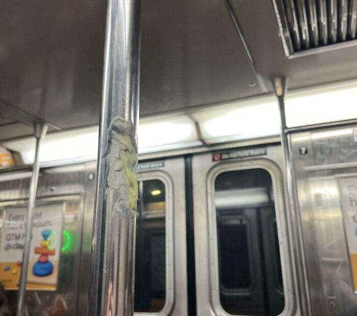 Металлический поручень в вагоне метро с прилипшей жвачкой