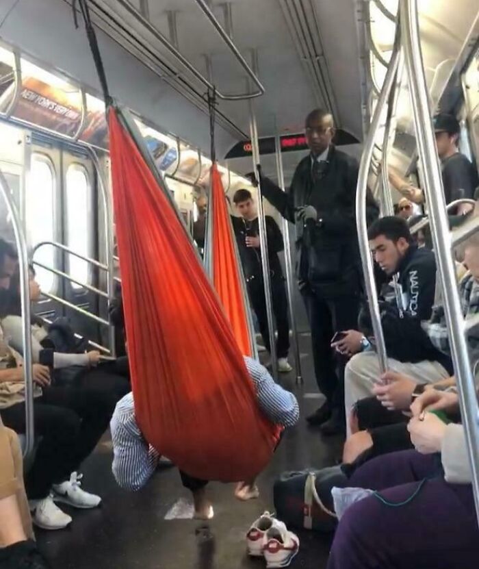 Человек отдыхает в красном гамаке подвешенном в вагоне метро