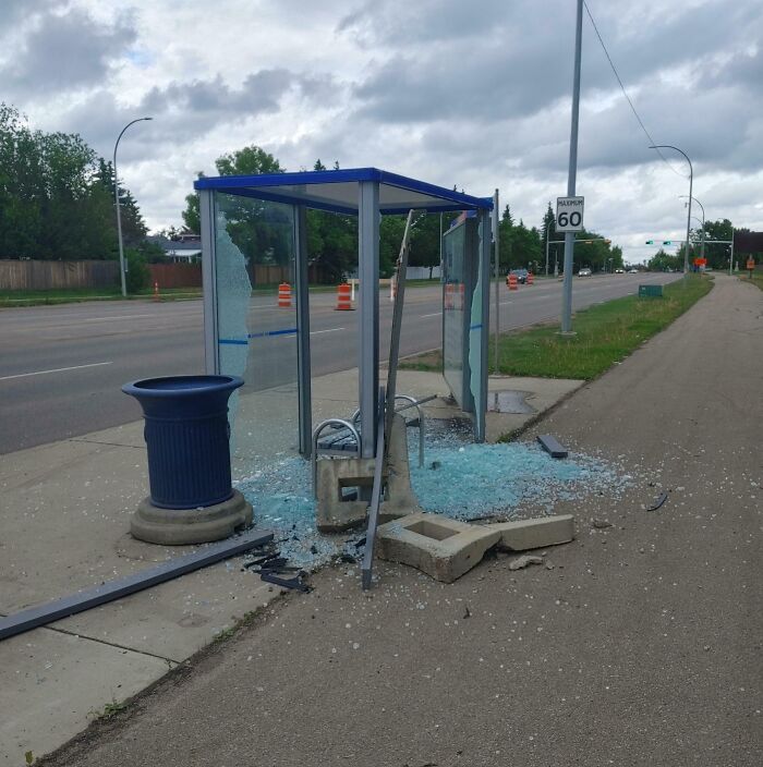 Разрушенная остановка с битым стеклом и бетонными обломками на тротуаре