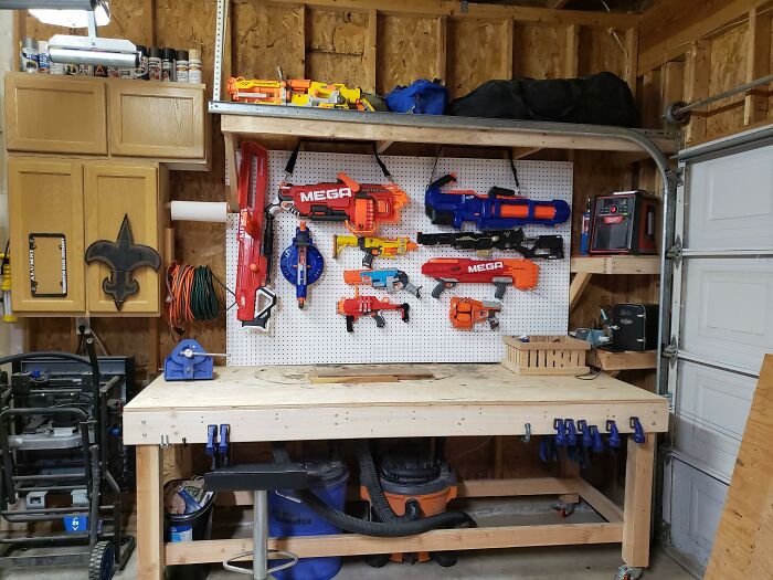 Большая коллекция ярких игрушечных бластеров на стене гаража