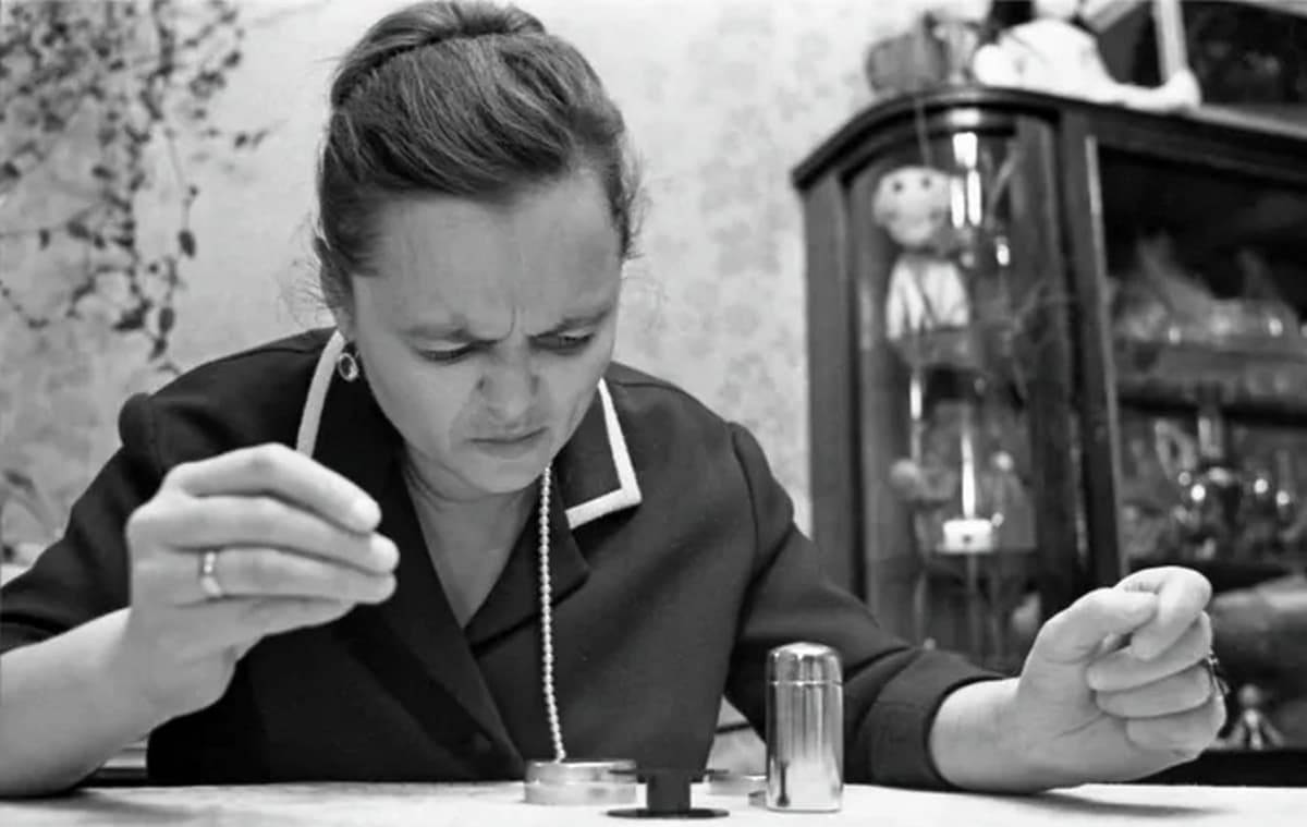 Кулагина сидит за столом у себя дома на столе мелкие предметы