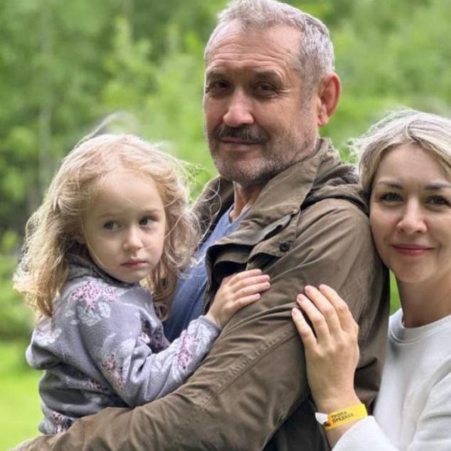 Семейное фото Усольцевых: Сергей, Ирина и их маленькая дочь Арина позируют в обнимку в помещении