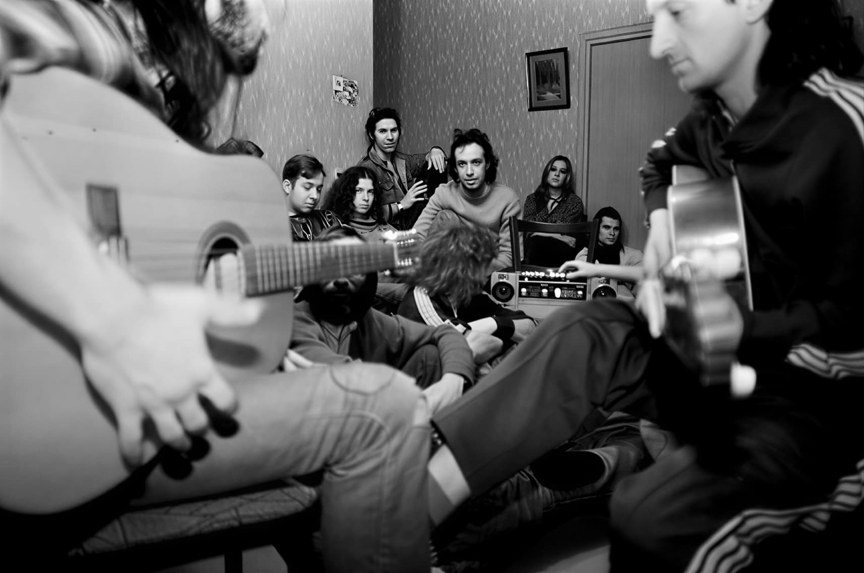 Неформальная атмосфера квартирника в Москве 1980-е, хиппи с гитарой слушают рок-музыку