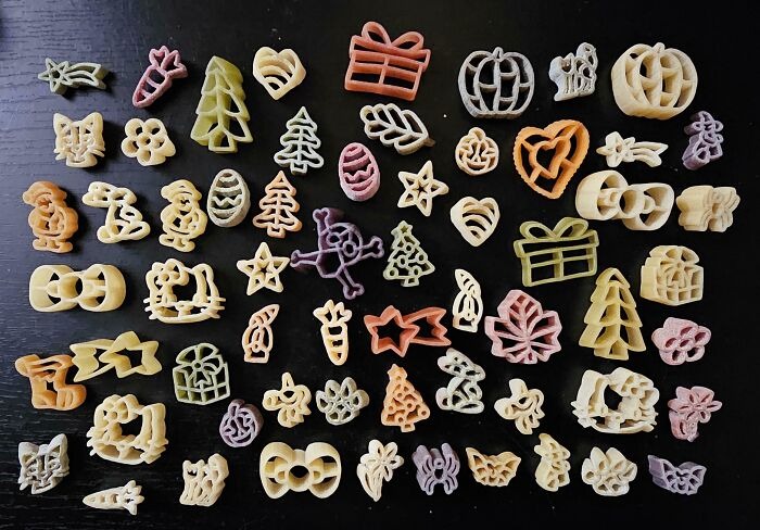 Разноцветные фигурные макароны разных форм разложены на чёрном столе