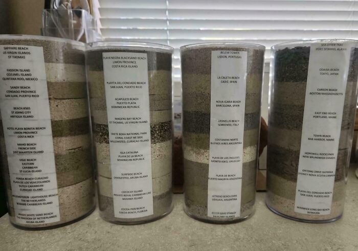 Коллекция разных видов песка в прозрачных банках с наклейками с названиями мест, где он был собран