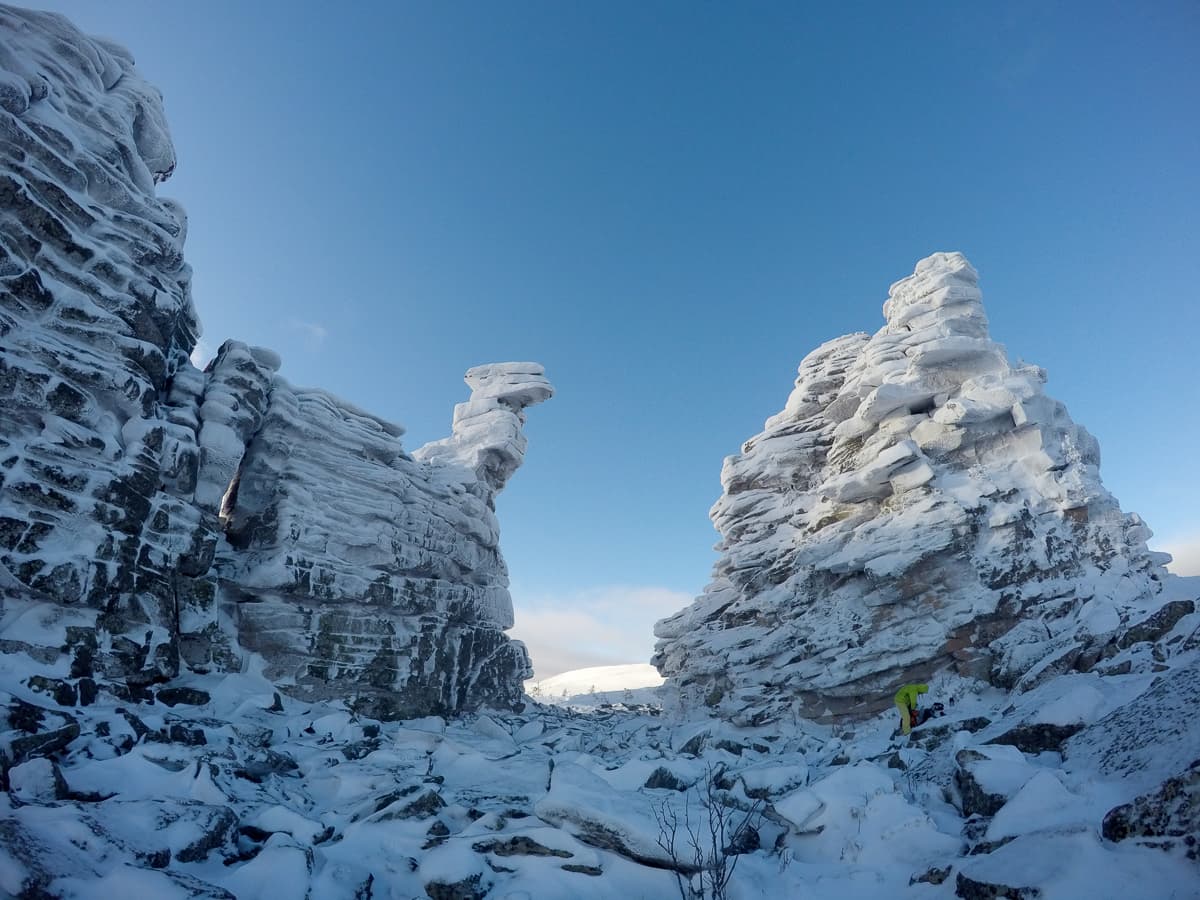 Заснеженные скалистые гребни и хаотичные нагромождения камней (курумник) на фоне пасмурного неба