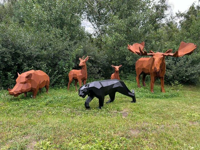 Группа полигональных животных из ржавого металла в саду, садовая скульптура