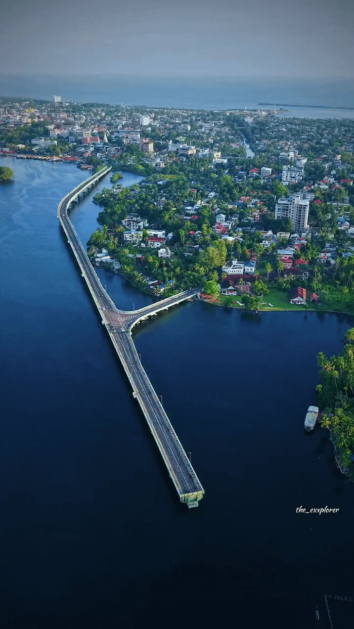 Длинный мост через воду к зелёному прибрежному району