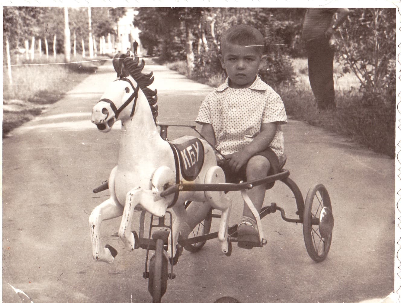 Детский прокат в парке культуры СССР. Несколько педальных автомобилей и мотоциклов стоят в ряд. За ними видна очередь из детей.