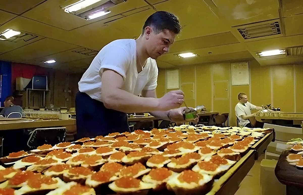 Стеклянная банка с красной икрой и кусок белого хлеба на столе &mdash; часть рациона подводников.