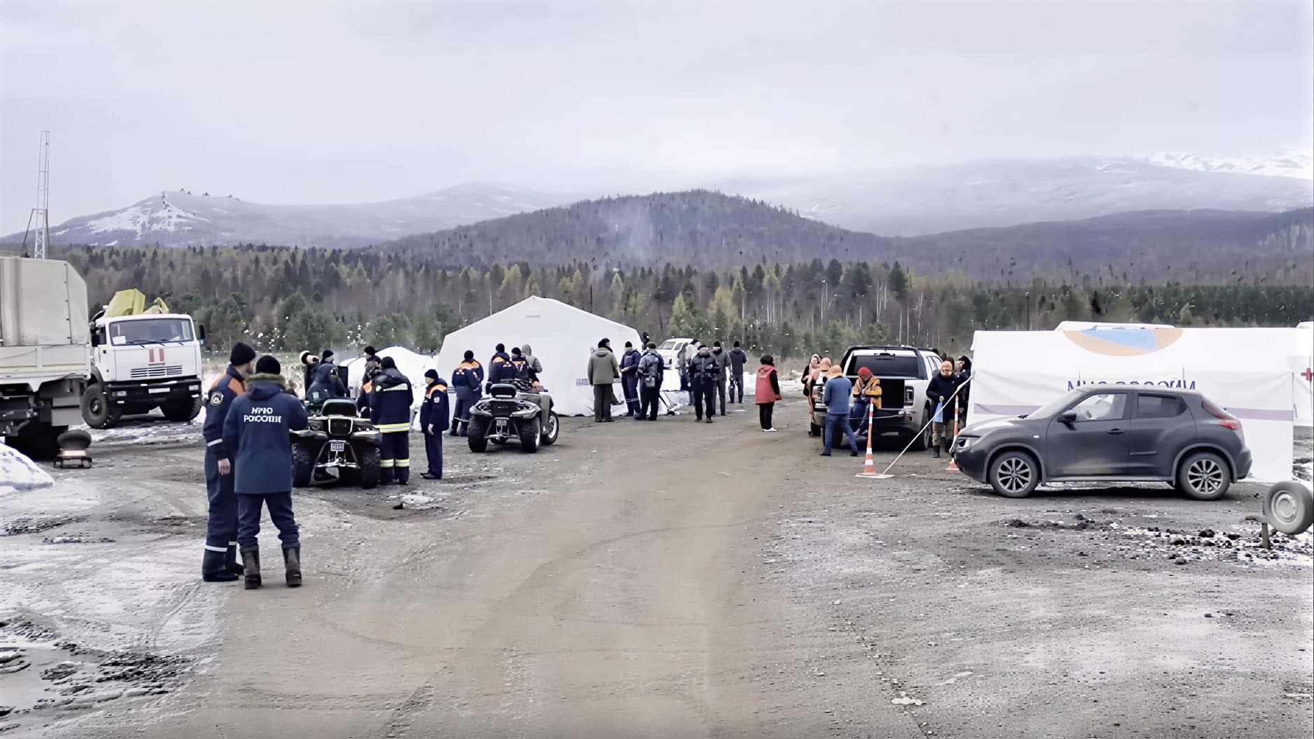 Штаб поисковой операции: волонтёры ЛизаАлерт в оранжевых футболках за компьютерами и с картами в полевом лагере