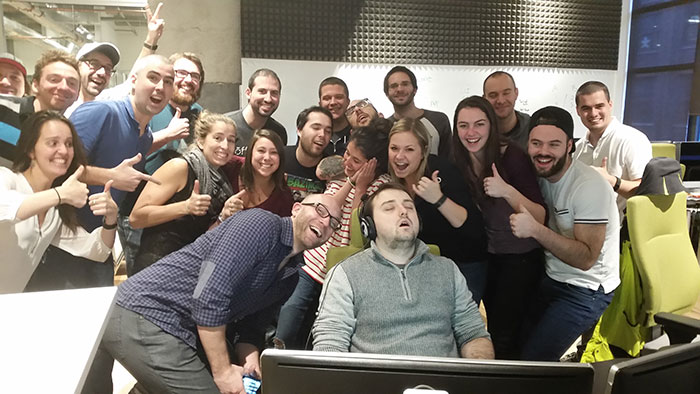 Коллеги позируют вокруг спящего мужчины за компьютером