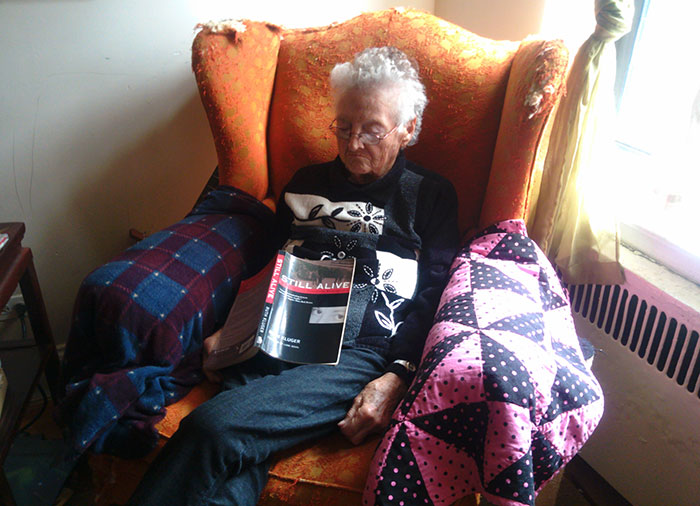 Пожилая женщина спит в кресле с книгой на коленях