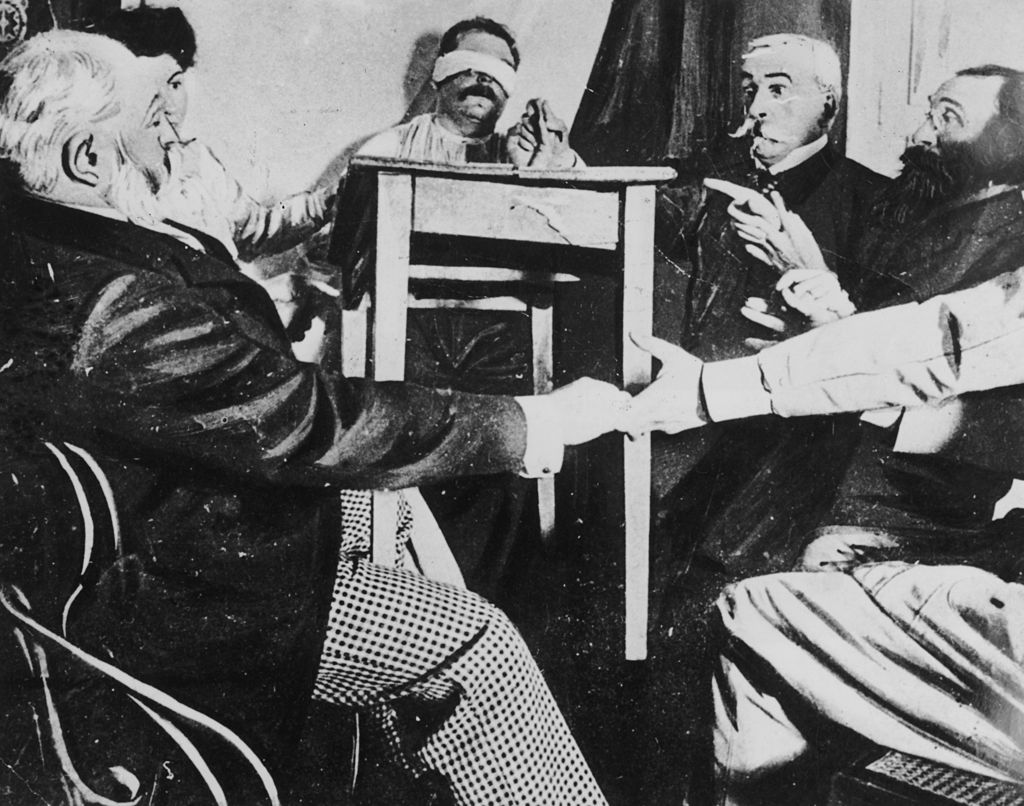 A group of people in France hold a seance in an attempt to make contact with the dead, circa 1870. 