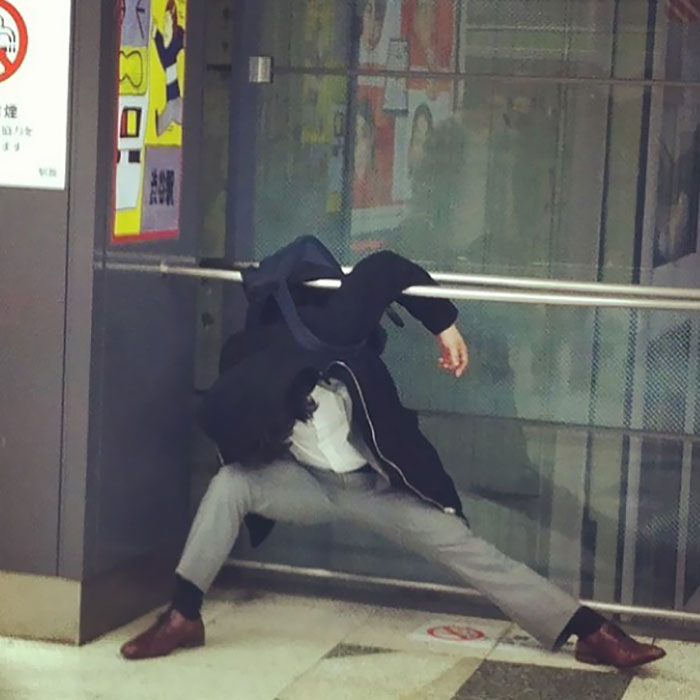 Человек в костюме спит между металлическими поручнями в неудобной позе