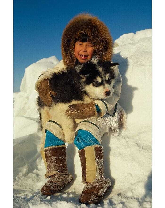 Девочка-инуит карибу держит щенка канадской эскимосской собаки