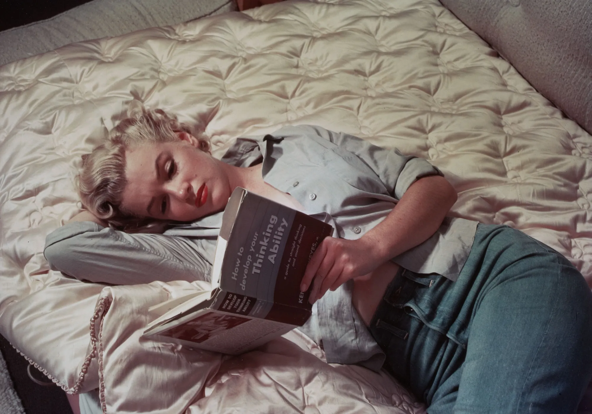 Крупный план Мэрилин Монро, которая держит раскрытую книгу и смотрит в неё, опровергая стереотип о недалёкой блондинке