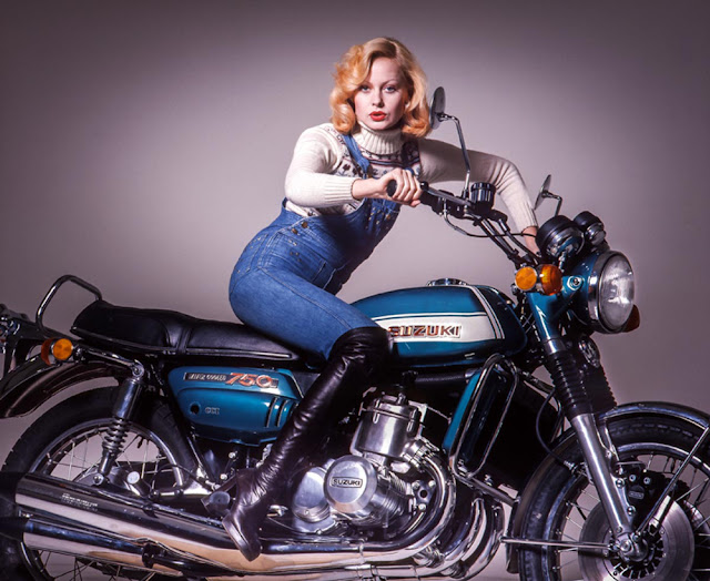 Женщина в джинсовом комбинезоне сидит на синем мотоцикле Suzuki 750