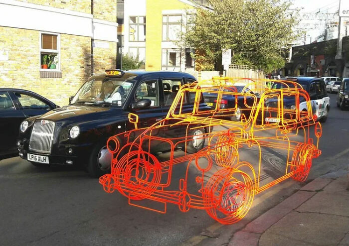 Чёрное лондонское такси рядом с оранжевым каркасом авто