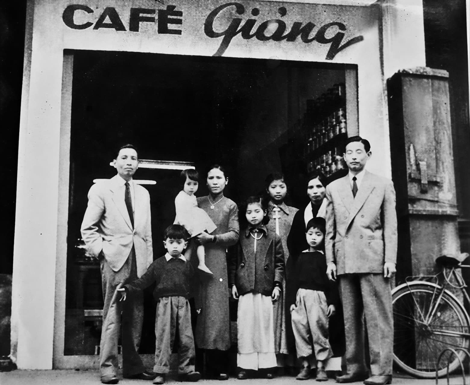 Историческое чёрно-белое фото: семья у входа в кафе Giảng, вывеска CAF&Eacute; Giảng, Ханой