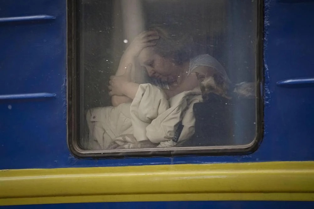 Женщина обнимает собачку в окне вагона поезда