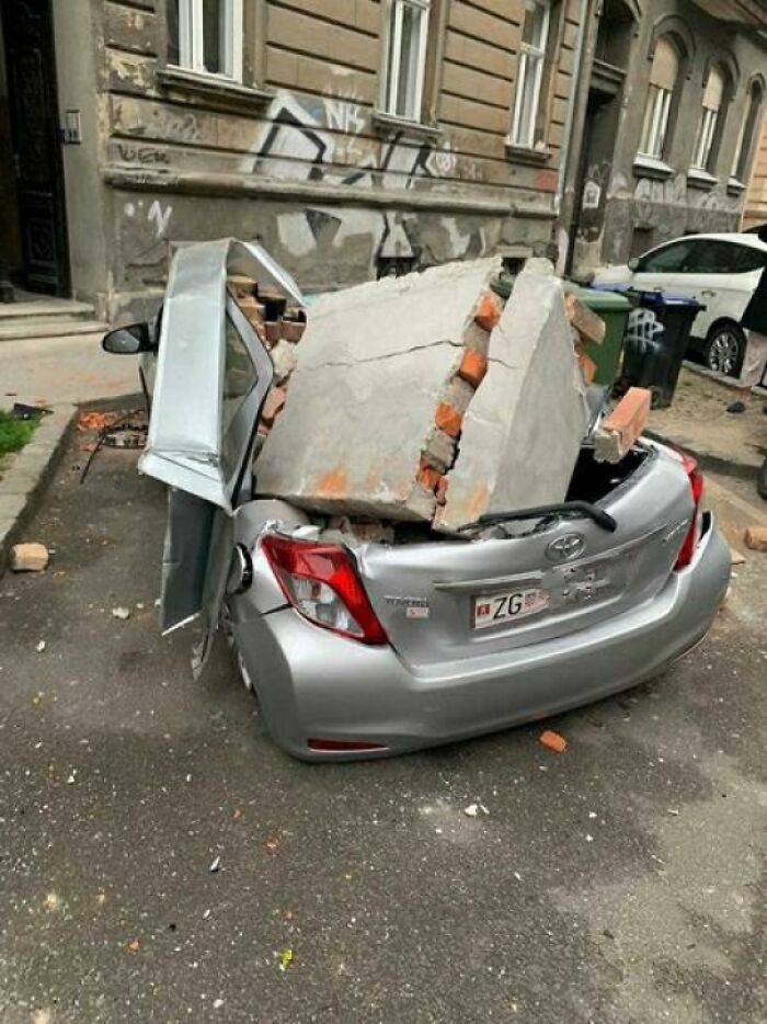 Серебристый автомобиль раздавлен бетонной плитой с кирпичами