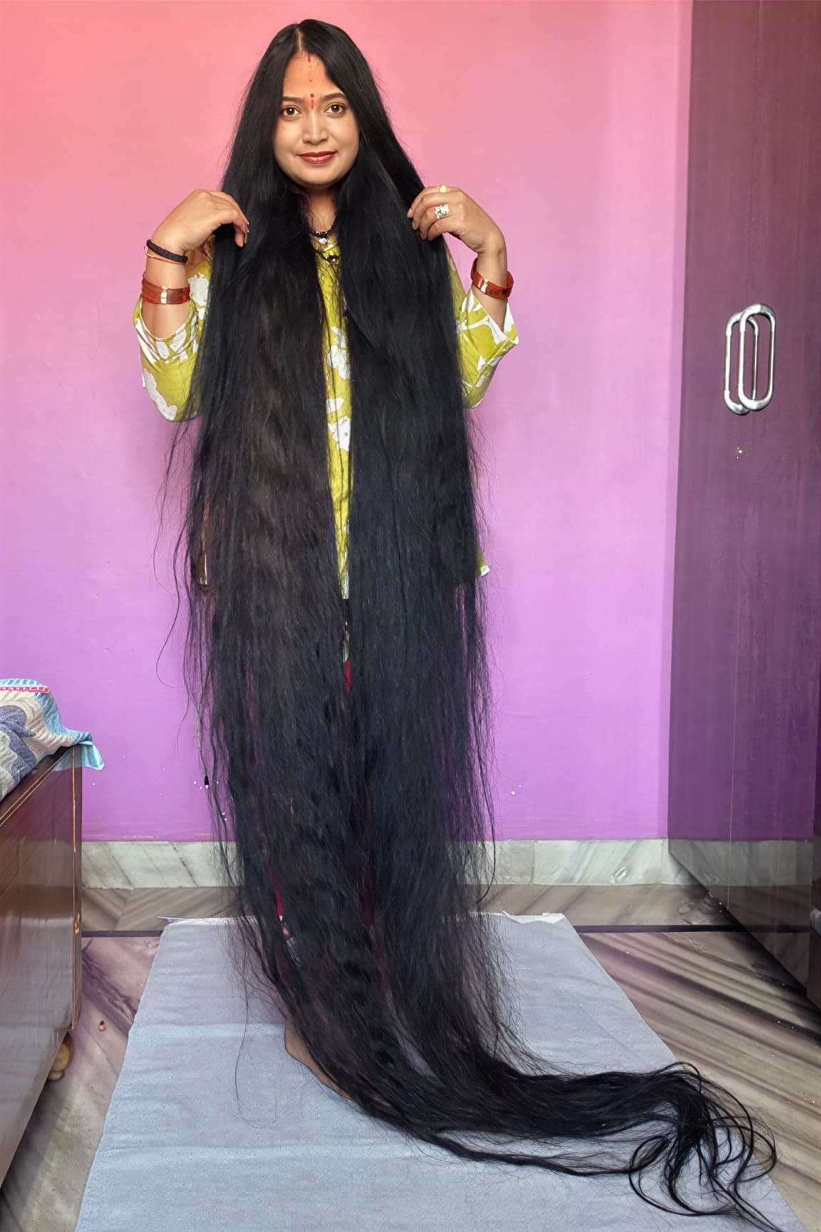 Рену Дхариял стоит, вокруг неё разложены волосы длиной 271,5 сантиметра