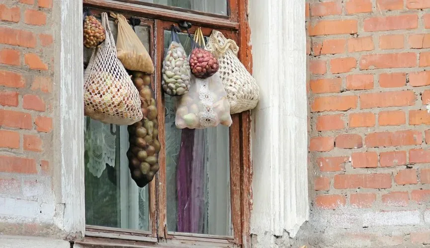 Авоська с продуктами, подвешенная за окном многоквартирного дома зимой